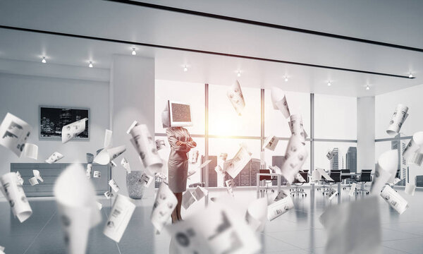 Деловая женщина в костюме с монитором вместо головы держит руки скрещенными, стоя среди летающих бумаг внутри офисного здания. 3D рендеринг
.