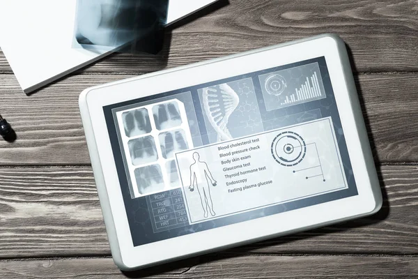 White tablet pc and doctor tools on wooden table