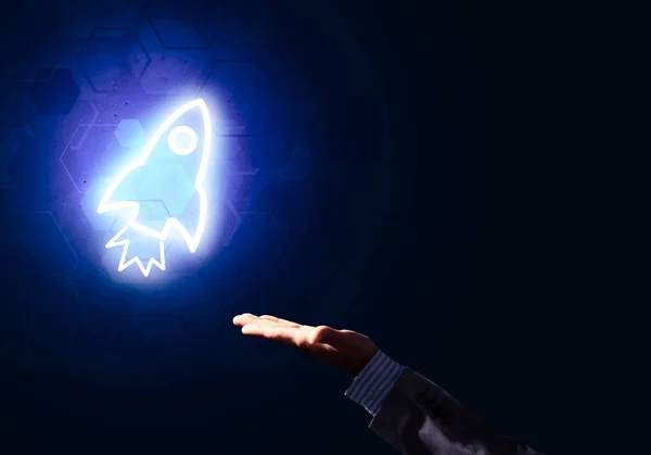 ロケット輝くアイコンと暗い背景にビジネスマンの手 — ストック写真