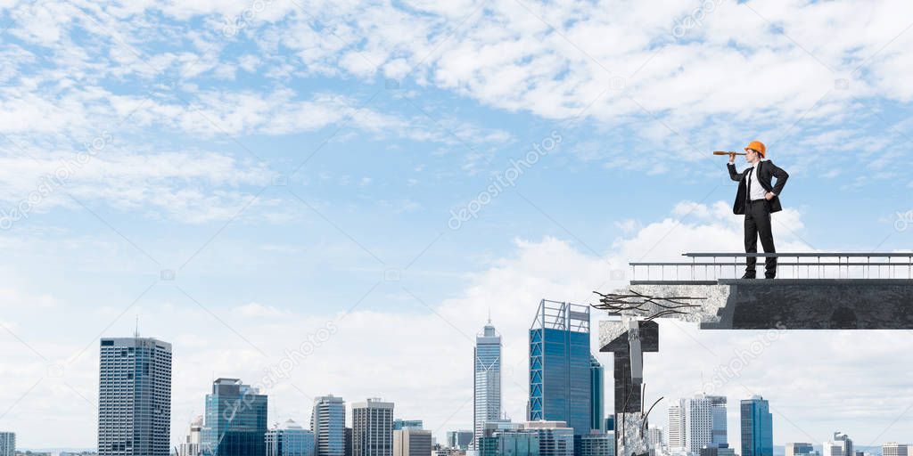 Young engineer in suit and helmet looking in spyglass while standing on broken bridge with cityscape on background. 3D rendering.