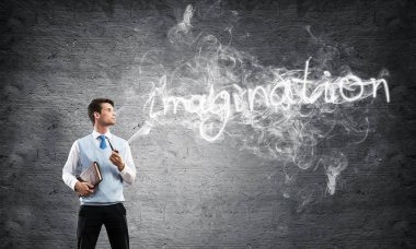 Akıllı-rahat, kendinden emin ve genç işadamı yatay atış yasaktır boru gri karanlık duvar ve duman arka plan üzerinde yapılan hayal word karşı dururken giymek.