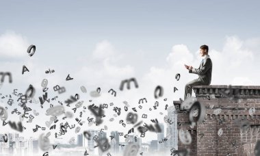 Elinde smartphone ile üst yapı üzerinde oturan genç işadamı