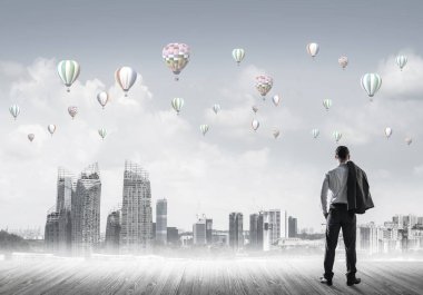 Arka ayakta ve havada uçan aerostats bakarak bir işadamı