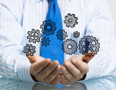 Masada oturan ve dişli mekanizması avuç içi gösterilen işadamı yakın çekim