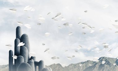 Açık havada, arka planda güzel manzarası olan uçan kağıt uçaklar arasında yer alan yüksek ve büyük taş sütunların resmi. Duvar kağıdı, telif alanı olan arkaplan.