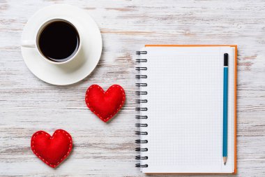 Kahve fincanı not defteri kalem ve ahşap yüzeyde iki kırmızı kalp