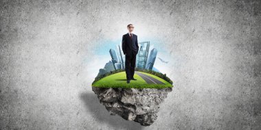 Yeşil yüzen adada beton zemine karşı duran kendine güvenen zarif iş adamı.