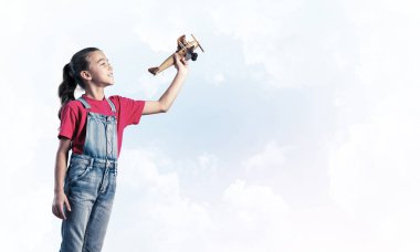 Elinde retro uçak modeliyle tulumlu şirin bir kız çocuğu.