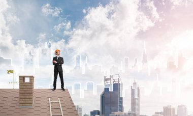 Takım elbiseli genç işadamı ve çatıda kask var. Karışık ortam