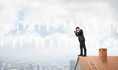 Genç işadamı dürbünüyle şehir manzarasını izliyor. Karışık ortam