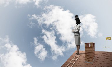 Evin çatısında baş durmak yerine kamerayla zum yapan yüzsüz iş kadını.