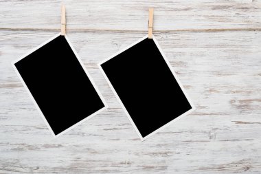 Boş fotoğraf çerçevesi ahşap bir zeminde ipte asılı.