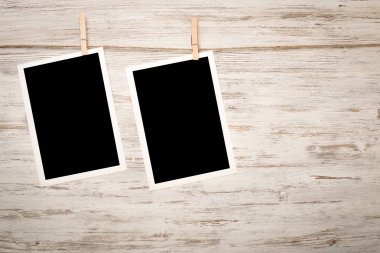 Boş fotoğraf çerçevesi ahşap bir zeminde ipte asılı.