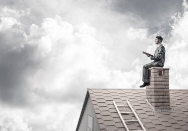 Elinde kırmızı kitap ile ev oturan takım elbiseli genç işadamı