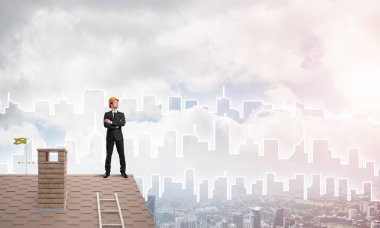 Takım elbiseli genç işadamı ve çatıda kask var. Karışık ortam