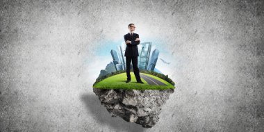 Yeşil yüzen adada beton zemine karşı duran kendine güvenen zarif iş adamı.