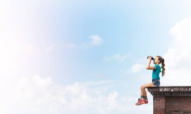 Dürbünle bakan, okul çağındaki sevimli kız çatıyı inşa ediyor.