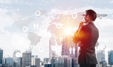 Çenesinde elleri olan genç ve zarif bir iş adamı başka tarafa bakıyor.