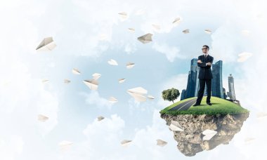 Mavi gök yeşil yüzen ada üzerinde duran zarif emin iş adamı