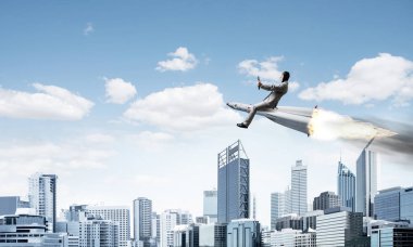 Arka plan üzerinde modern cityscape gökdelenler ve mavi gökyüzü ile roket üzerinde uçan takım elbiseli genç işadamı kavramsal görüntü.