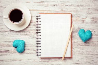 Kahve fincanı not defteri kalem ve ahşap yüzeyde iki kalp