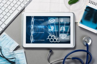 Gri yüzeyde beyaz tablet ve doktor araçları