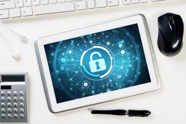 Ofis eşyalarıyla iş yeri ve ekranda asma kilit simgesi olan tablet