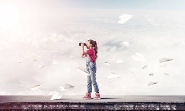 Dürbünle bakan, okul çağındaki sevimli kız çatıyı inşa ediyor.