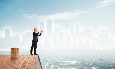 Takım elbiseli genç işadamı ve çatıda kask var. Karışık ortam