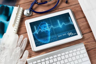 Beyaz tablet bilgisayar ve doktor aletleri ahşap masada.