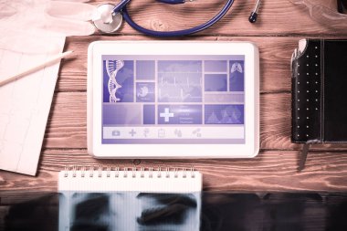Beyaz tablet bilgisayar ve doktor aletleri ahşap masada.