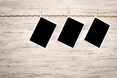 Boş fotoğraf çerçevesi ahşap bir zeminde ipte asılı.