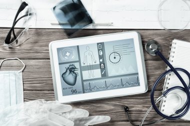Beyaz tablet bilgisayar ve doktor aletleri ahşap masada.