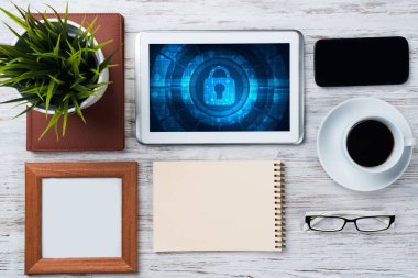 Ofis eşyalarıyla iş yeri ve ekranda asma kilit simgeleri olan tablet