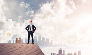 Takım elbiseli genç işadamı ve çatıda kask var. Karışık ortam