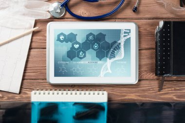 Beyaz tablet bilgisayar ve doktor aletleri ahşap masada.