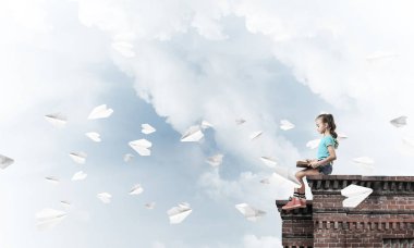 Çatı ve kitap okumak binasında oturan sevimli kız