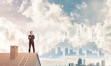 Takım elbiseli genç işadamı ve çatıda kask var. Karışık ortam