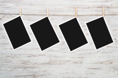 Boş fotoğraf çerçevesi ahşap bir zeminde ipte asılı.