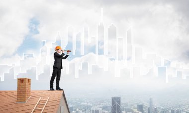 Takım elbiseli genç işadamı ve çatıda kask var. Karışık ortam