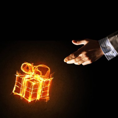 Parlayan yangın hediye kutusu simgesinin koyu arka plan üzerine gösteren işadamı ele
