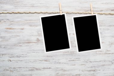 Boş fotoğraf çerçevesi ahşap bir zeminde ipte asılı.