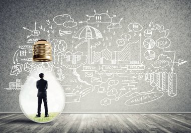 Boş beton odada ampulün içindeki iş adamı ve duvardaki çizimler