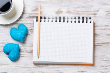 Kahve fincanı not defteri kalem ve ahşap yüzeyde iki kalp