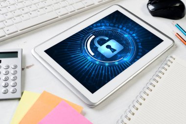 Ofis eşyalarıyla iş yeri ve ekranda asma kilit simgesi olan tablet