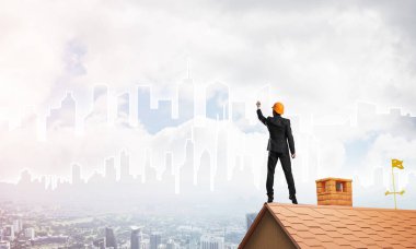 Mühendis, evinin çatısına geri döndü ve şehri çiziyor. Karışık ortam