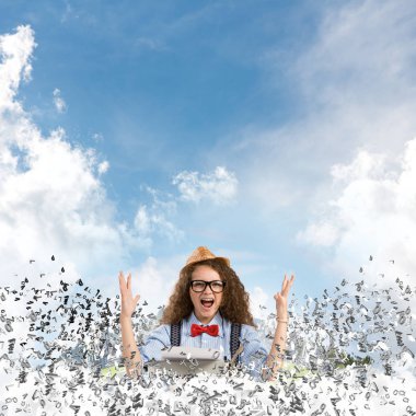 Mutlu bir kadın yazar şapka ve gözlük harfler yüzen Şehir Adası ve bulutlu gökyüzü arka plan üzerinde uçan arasında masadaki otururken yazarak makinasıyla.