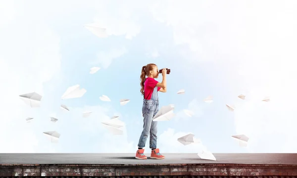 かわいいです女の子の学校年齢の建物屋根見ますで双眼鏡 — ストック写真