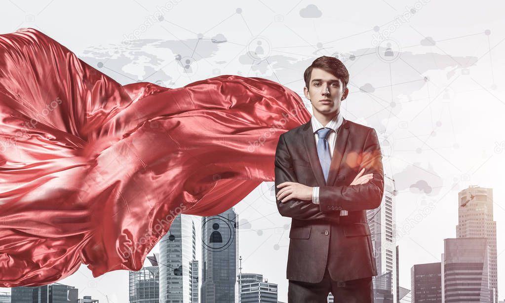 Young confident businessman wearing red cape against modern city background