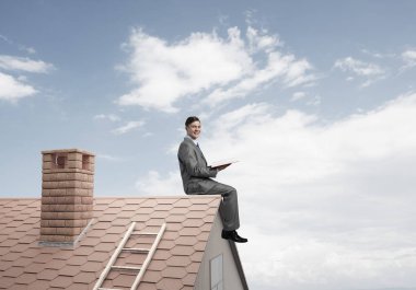 Elinde kırmızı kitap ile ev oturan takım elbiseli genç işadamı